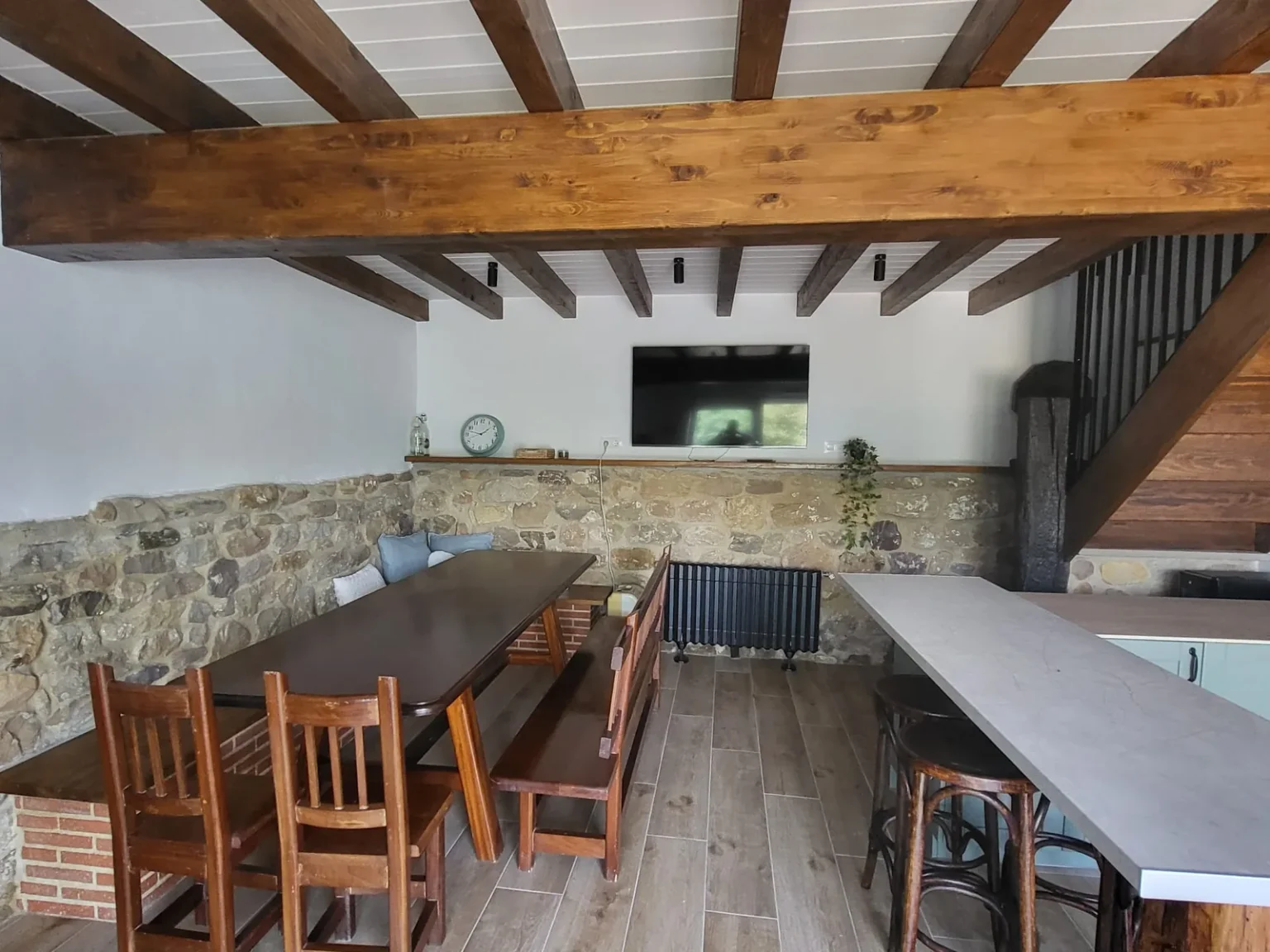 Cocina-comedor con mesa larga bajo vigas de madera