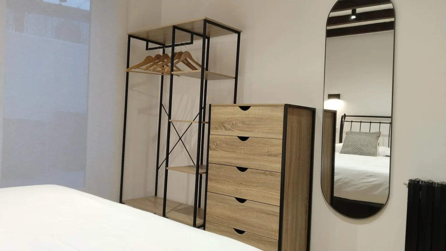 Habitación con armario abierto, cómoda y espejo