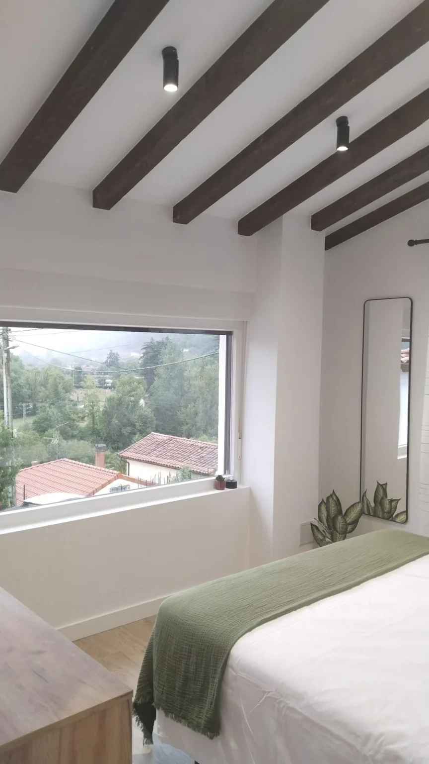 Habitación bajo vigas con ventana a las montañas
