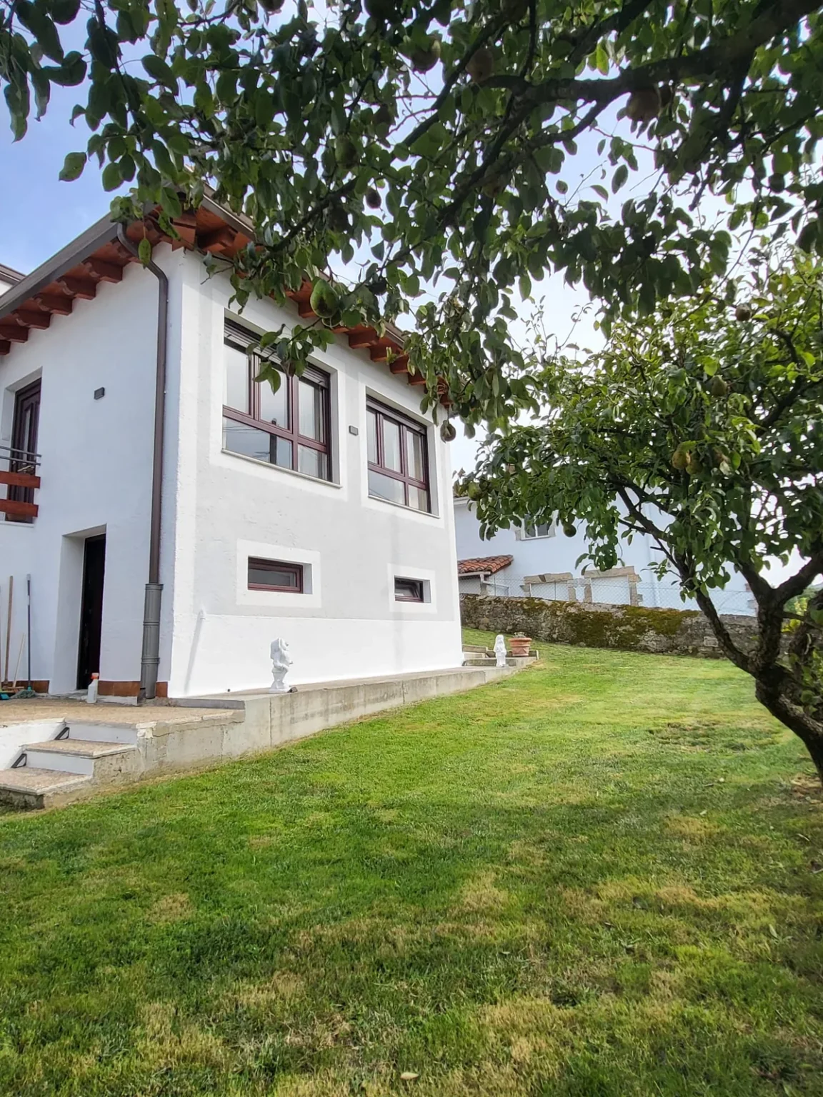 Jardín con césped y árbol frutal junto a la casa
